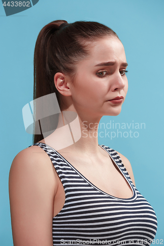 Image of The young woman is looking sad on the blue background.