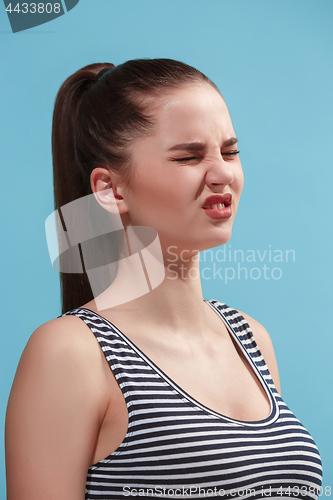 Image of The young woman is looking angry on the blue background.