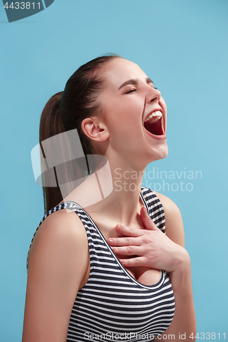 Image of The happy woman standing and smiling against blue background.