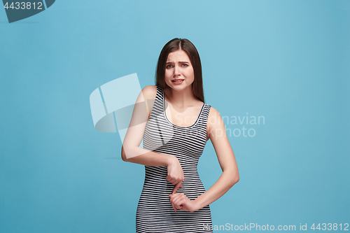 Image of The awkward woman standing and looking at camera against blue background.