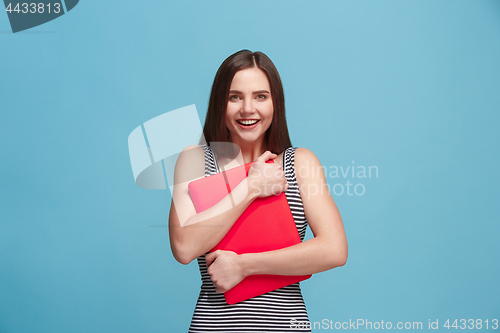 Image of Businesswoman hugging laptop on blue studio