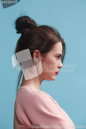 Image of The serious business woman standing against blue background.