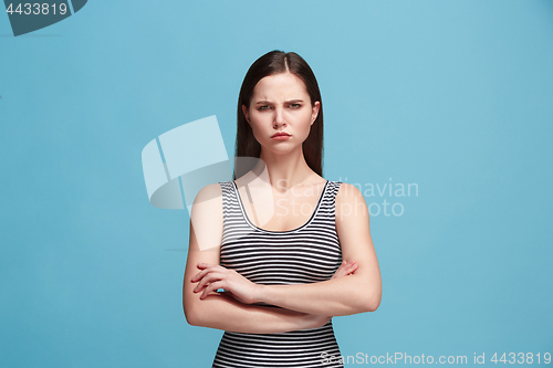 Image of The serious woman standing and looking at camera against blue background.