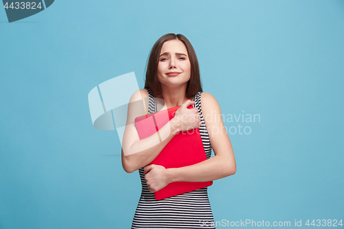 Image of Businesswoman hugging laptop on blue studio