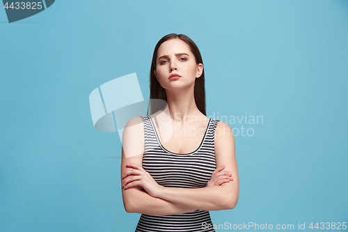 Image of The serious woman standing and looking at camera against blue background.