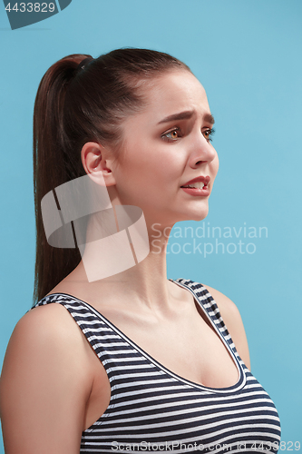 Image of The young woman is looking sad on the blue background.