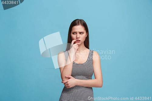 Image of Let me think. Doubtful pensive woman with thoughtful expression making choice against blue background