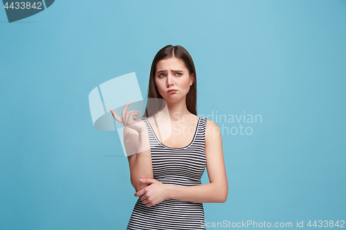 Image of Let me think. Doubtful pensive woman with thoughtful expression making choice against blue background