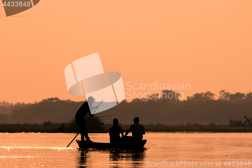 Image of Men in a boat on a river silhouette