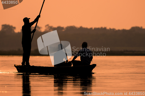Image of Men in a boat on a river silhouette