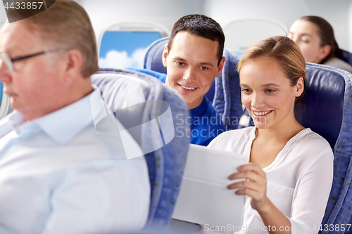 Image of happy passengers with coffee talking in plane