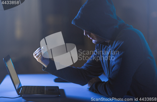 Image of hacker showing fist to laptop in dark room