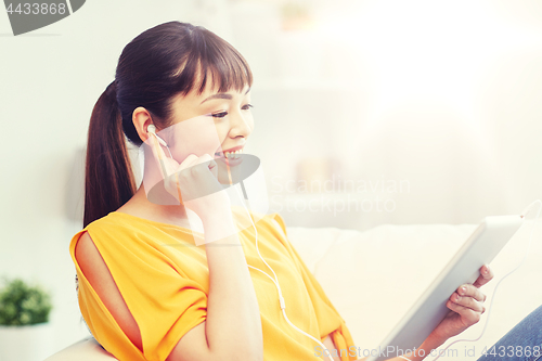 Image of happy asian woman with tablet pc and earphones