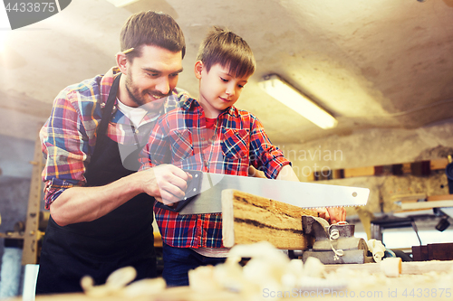 Image of father and son with saw working at workshop