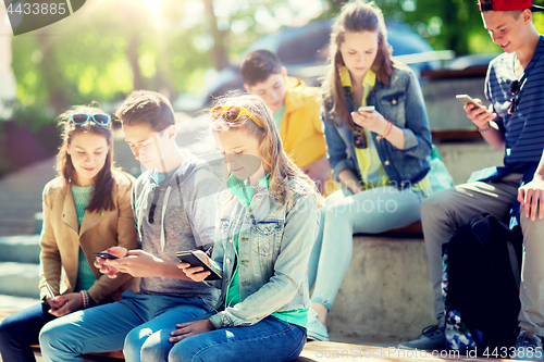 Image of teenage friends with smartphones outdoors