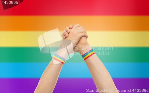 Image of hands with gay pride wristbands in winning gesture