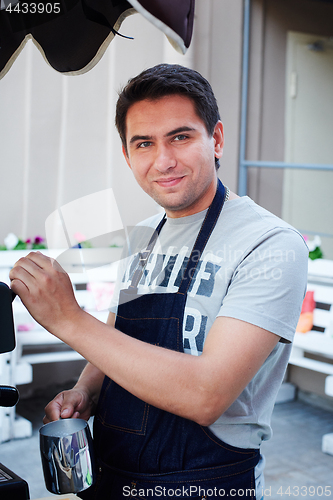 Image of Barista making coffee and looking at camera