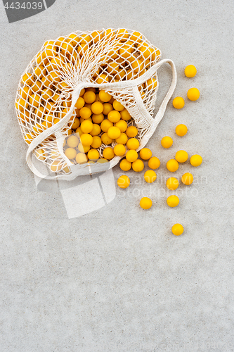 Image of Yellow plums in a mesh bag on concrete background