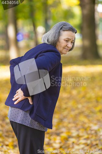 Image of Senior woman suffering from backache outdoors