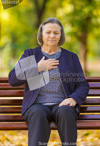 Image of Puzzled aging woman having heart attack outdoors