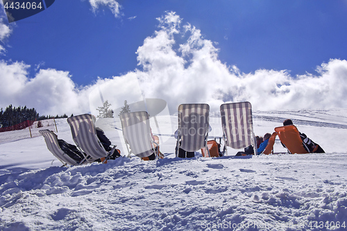 Image of Skiers sunbathing on the ski slope with blue sky background