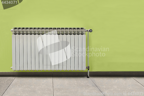 Image of White radiator in front of the green wall