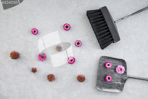 Image of Dustpan, brush and pink flowers on concrete floor