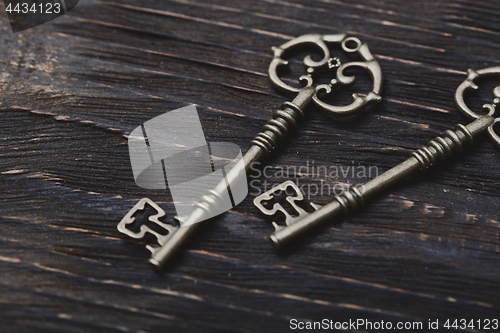 Image of Two vintage bronze keys on a wooden table