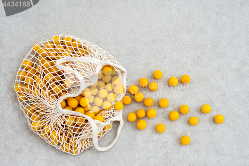 Image of Lots of yellow plums in a mesh shopping bag