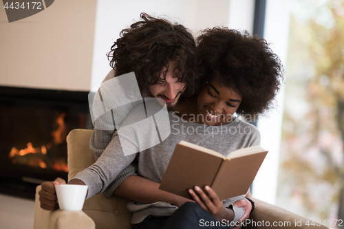 Image of multiethnic couple hugging in front of fireplace