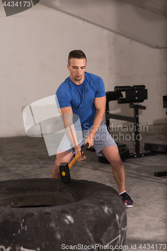 Image of man workout with hammer and tractor tire