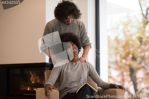 Image of multiethnic couple hugging in front of fireplace