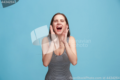 Image of Isolated on blue young casual woman shouting at studio