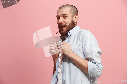 Image of The young man whispering a secret behind her hand over pink background