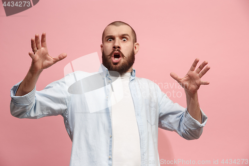 Image of The young attractive man looking suprised isolated on pink
