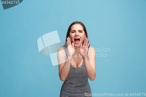 Image of Isolated on blue young casual woman shouting at studio