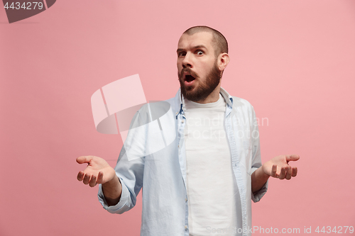 Image of Beautiful male half-length portrait isolated on pink studio backgroud. The young emotional surprised man