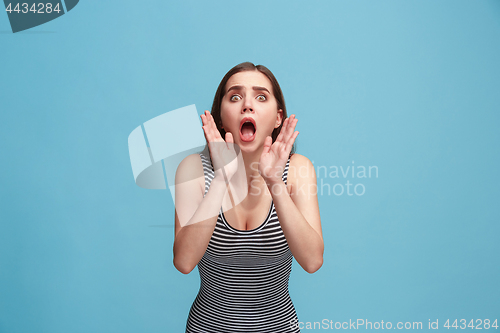 Image of Isolated on blue young casual woman shouting at studio