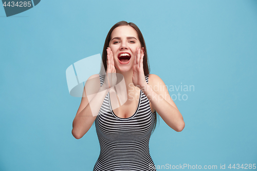 Image of Isolated on blue young casual woman shouting at studio