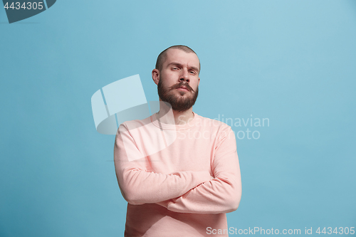 Image of The serious businessman standing and looking at camera against blue background.