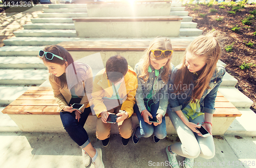 Image of happy teenage friends with smartphones outdoors