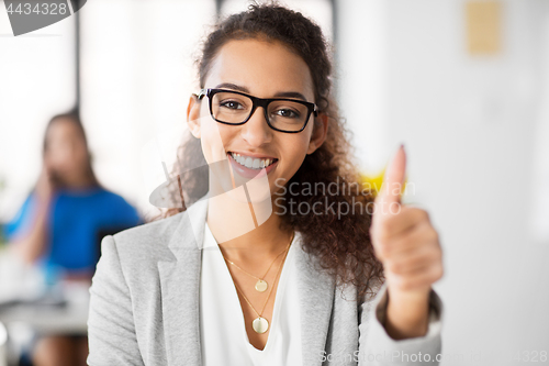 Image of smiling african woman showing thumbs up at office