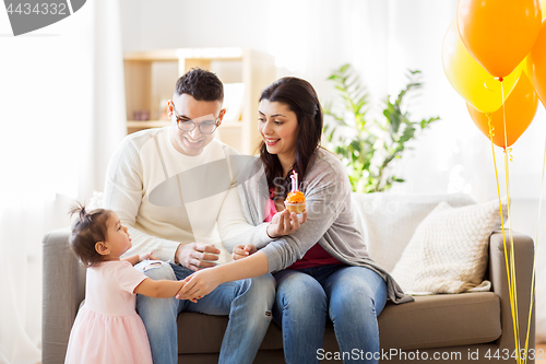 Image of baby girl with parents at home birthday party