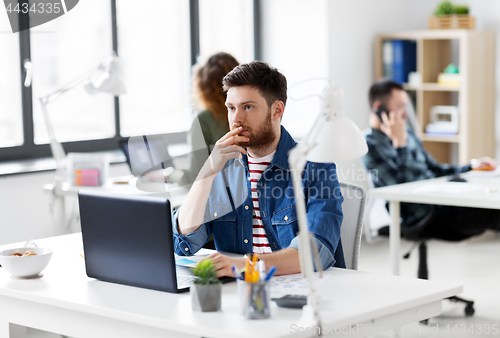 Image of creative man with laptop working at office