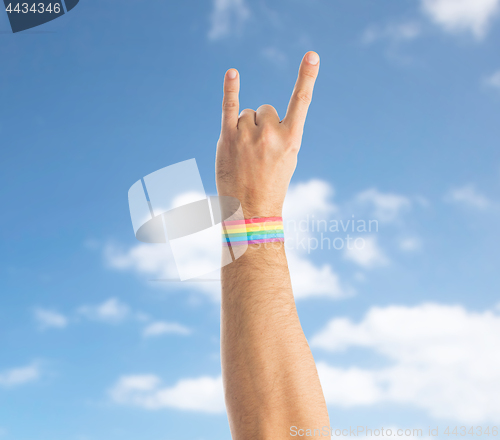 Image of hand with gay pride rainbow wristband shows rock