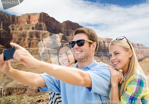 Image of group of happy friends taking selfie by cell phone