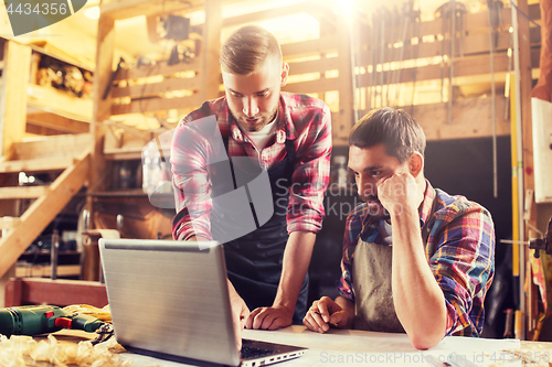 Image of carpenters with laptop and blueprint at workshop