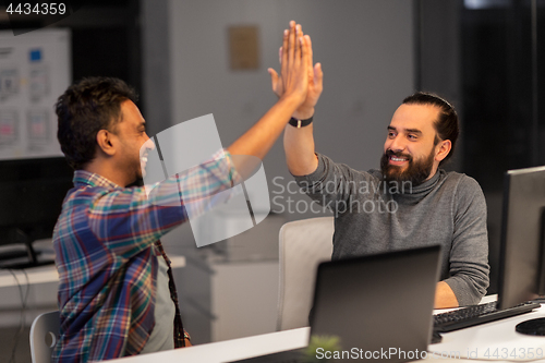 Image of creative team making high five at night office