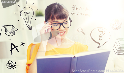 Image of smiling young asian woman reading book at home