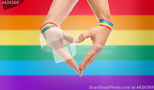 Image of male hands with gay pride wristbands showing heart